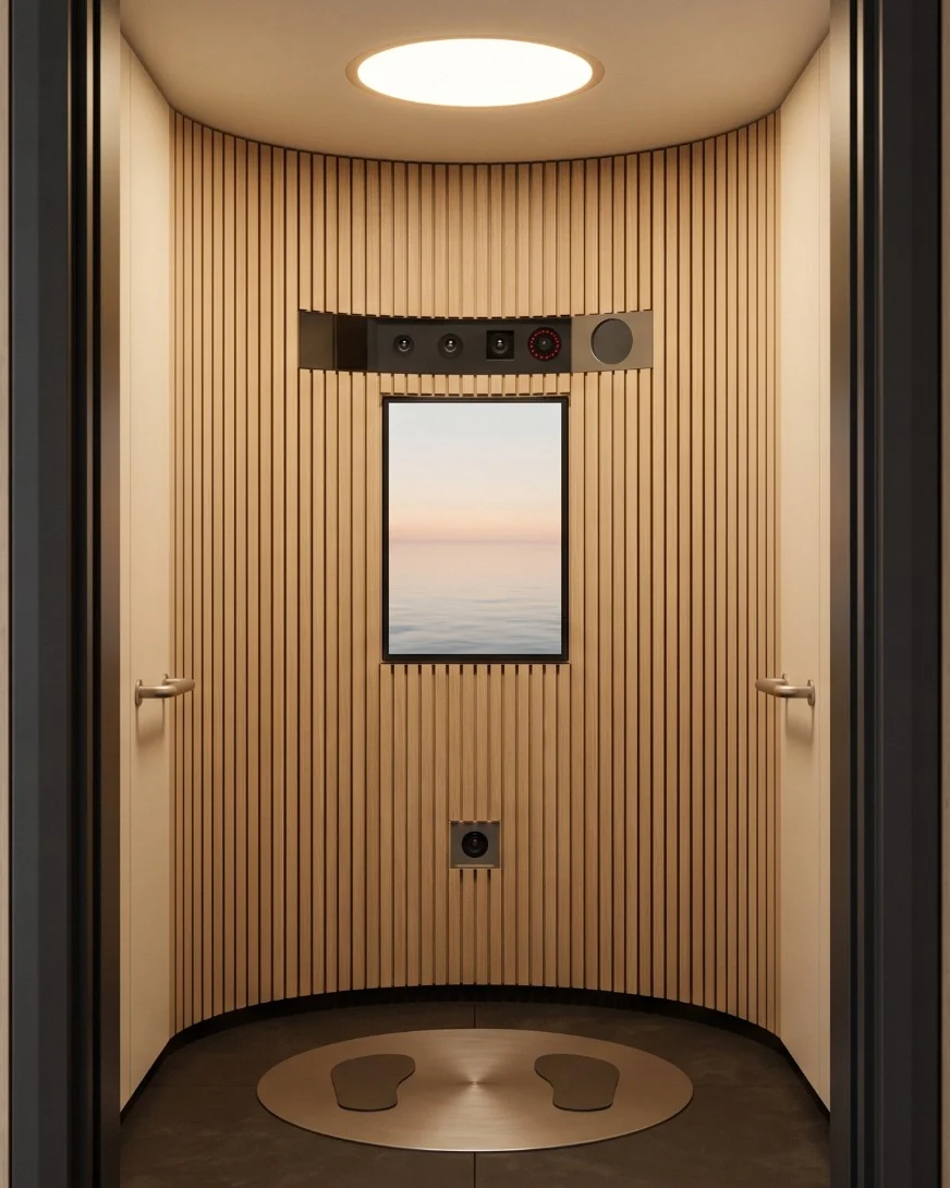 Inside Soma Axon through its open door: oak slats, a small screen showing the sea, a strip of cameras above it and a round floor plate with two foot pads
